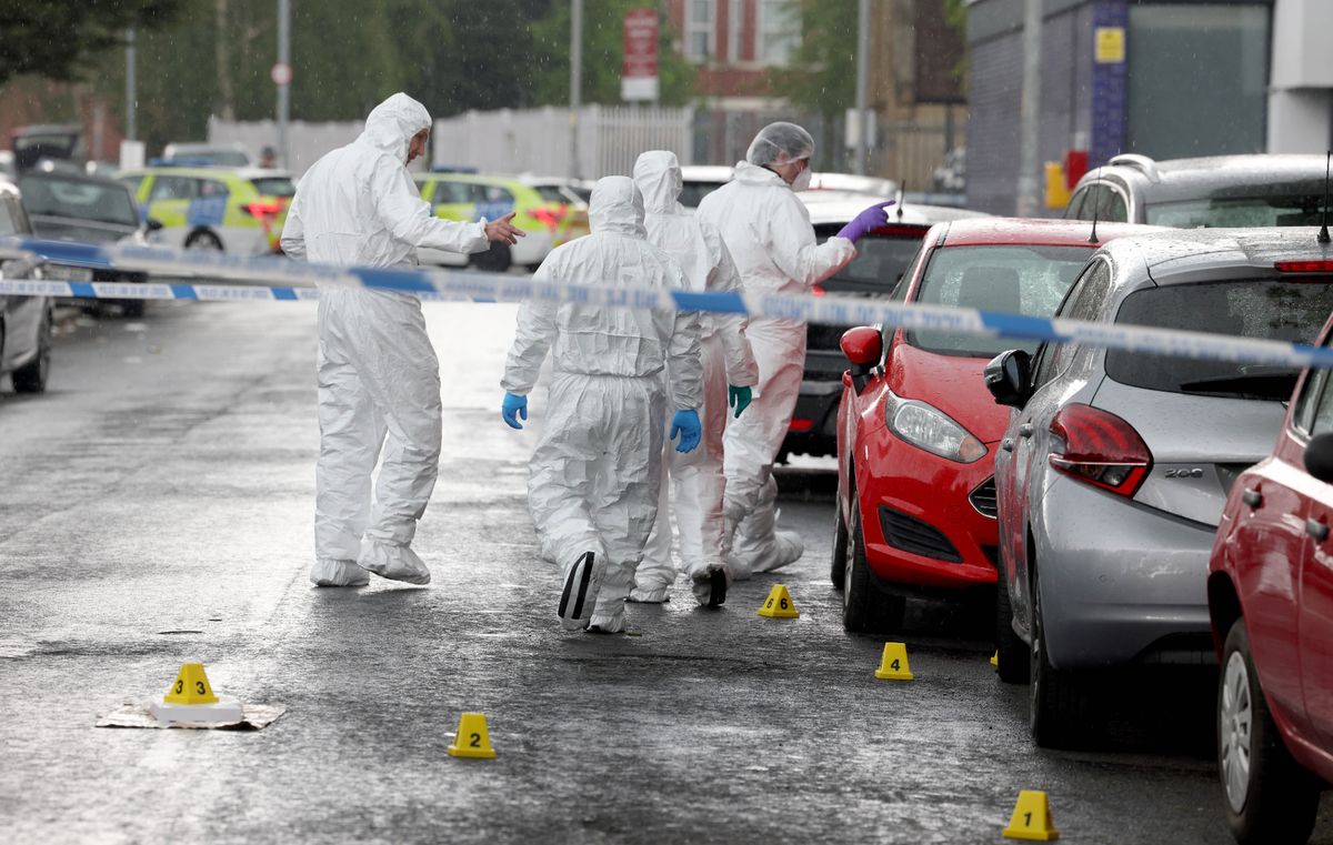 Police and forensics at the scene of a murder in Moss Side