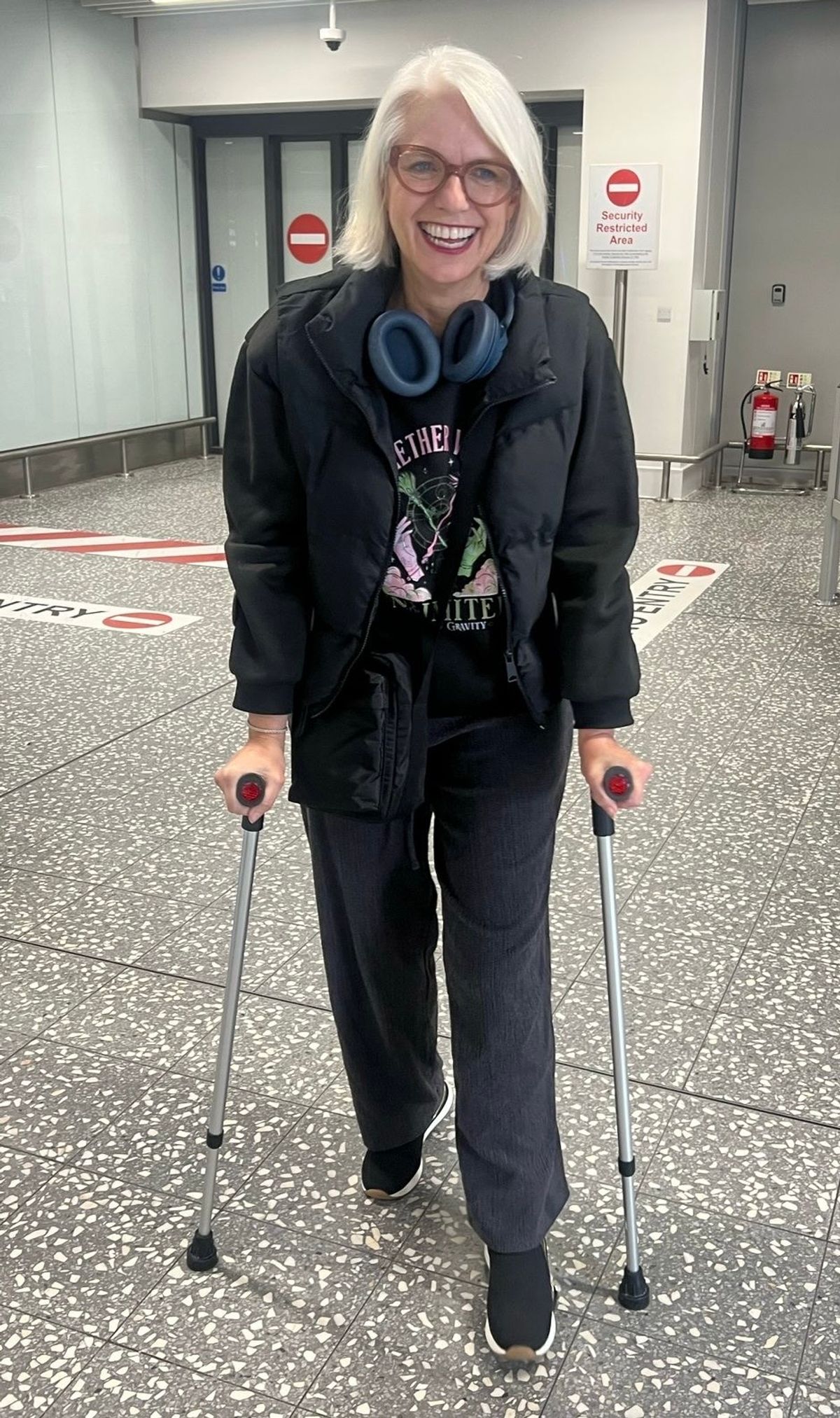 Woman smiling using crutches in an airport