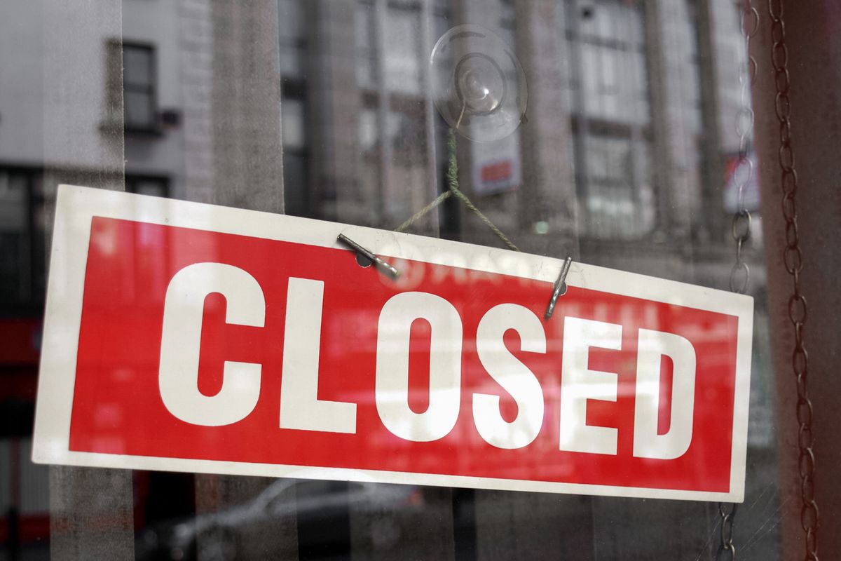 Closed sign in a shop showroom with reflections - red sign over desaturated background