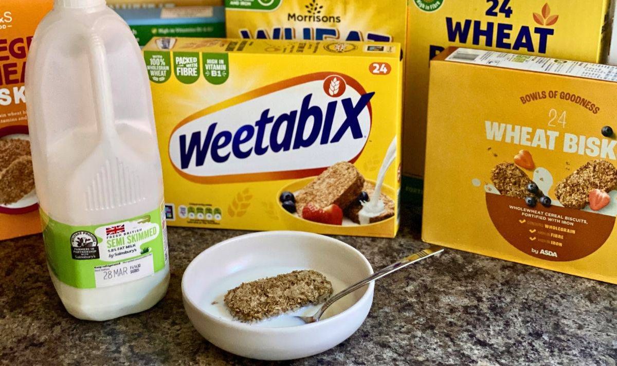Wheat biscuit in bowl of milk surrounding by boxes of cereal