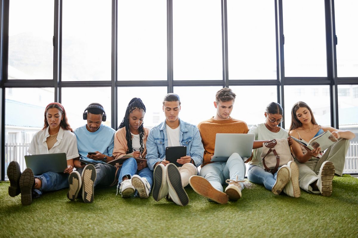 Group of people sitting in a line on the floor with their laptops