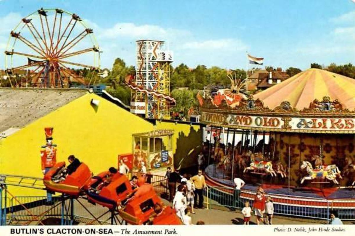 An aerial view of an amusement park featuring various attractions, including a Ferris wheel, a carousel, and other rides with visitors enjoying the activities.