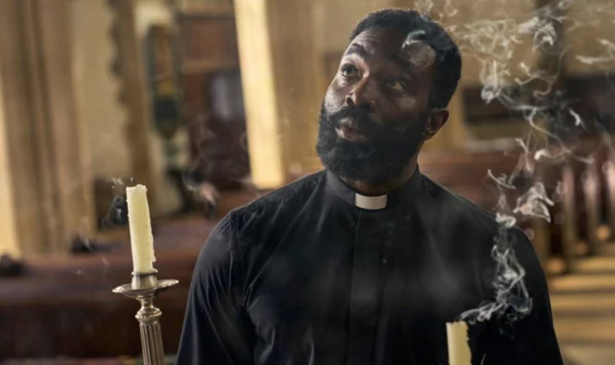 Bearded priest standing behind candles