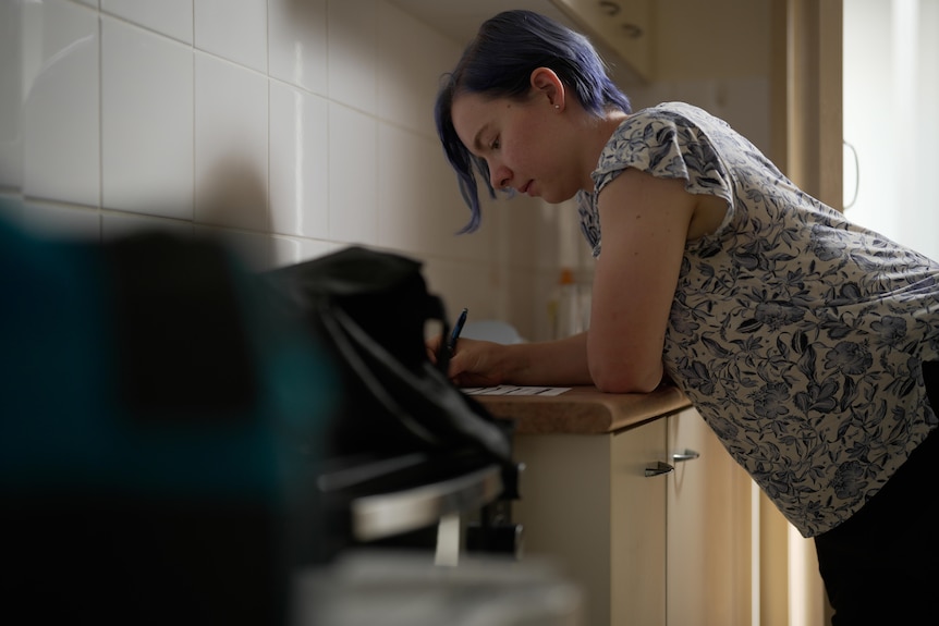 A woman leaning on her bench in the kitchen.