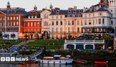 A row of buildings in front of a stepped lawn leading down to the River Thames.