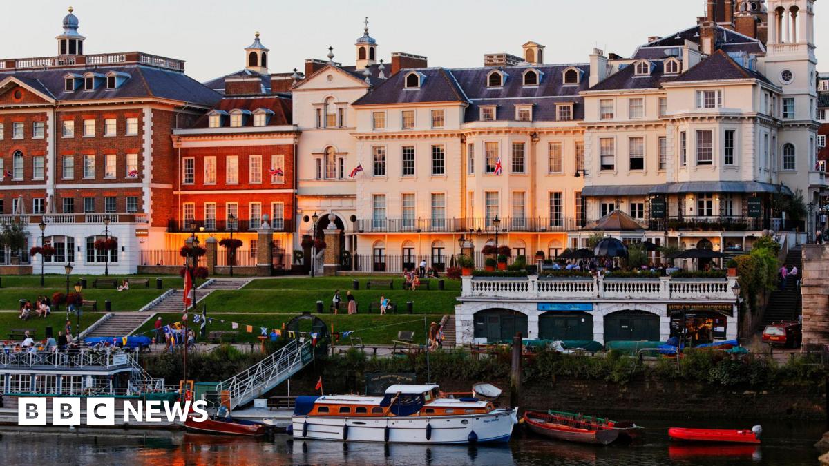A row of buildings in front of a stepped lawn leading down to the River Thames.