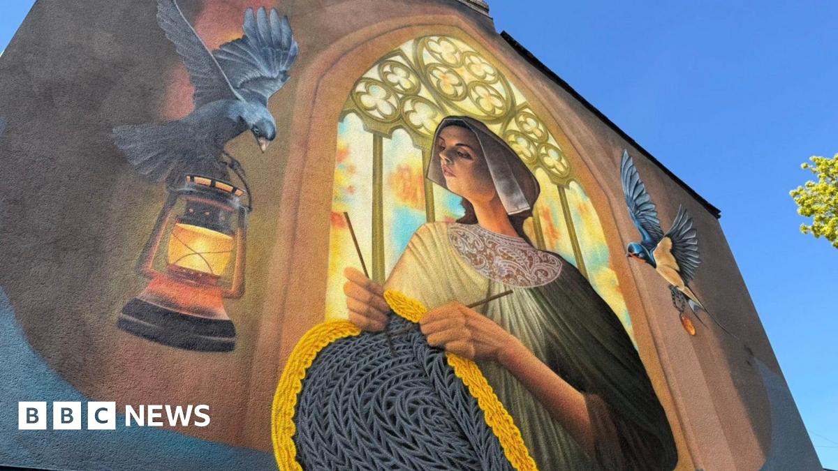 A colourful, large-scale wall painting showing a woman dressed in modest 19th Century clothing while knitting a woollen jumper. She is depicted standing in front of an arched church window through which light streams. To the left, a black bird carries a lamp. Another bird flies to the right.