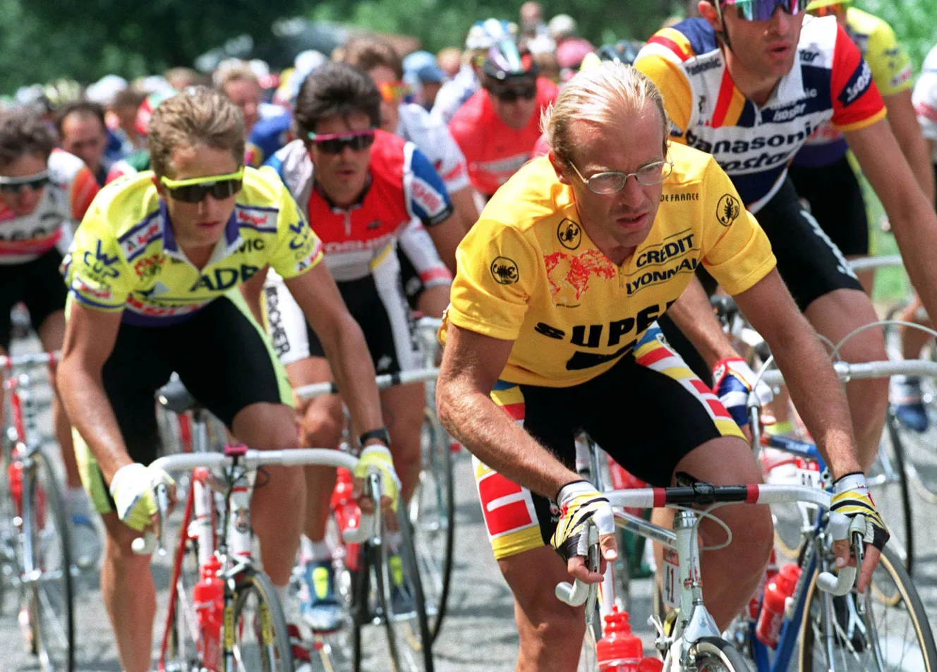 French cyclist Laurent Fignon (right) in a yellow jersey, and American cyclist Greg Lemond (left) in a white, red, and blue jersey, cycling side by side during the 11th stage of the 1989 Tour de France.