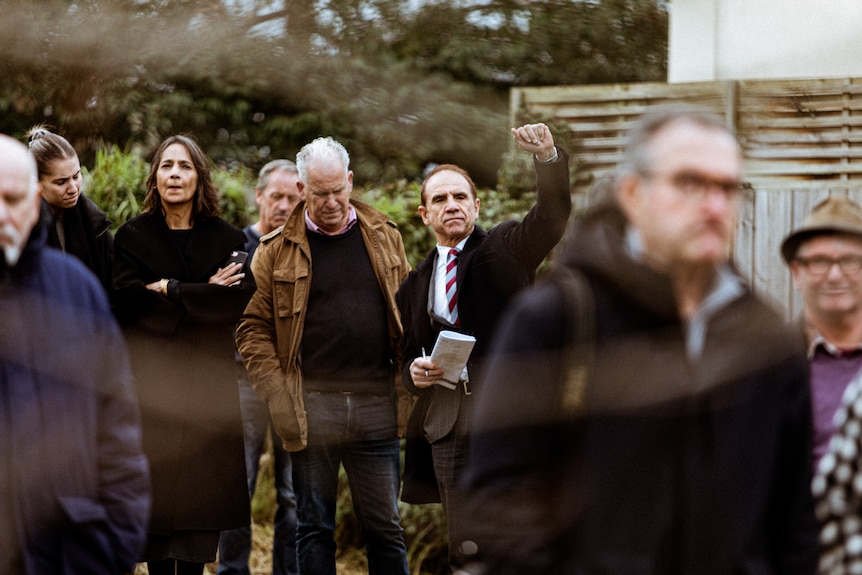People stand in a group, one man with his arm raised.