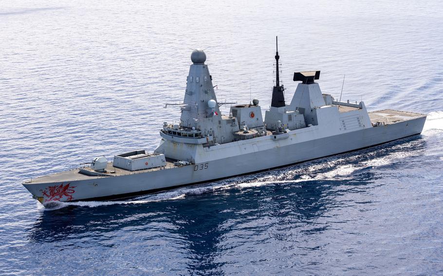 A naval destroyer, seen from above, sails in open ocean.
