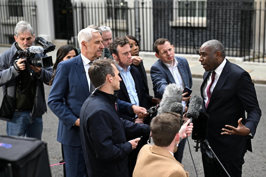 David Lammy speaking to a group of journalists surrounding him on Downing Street.