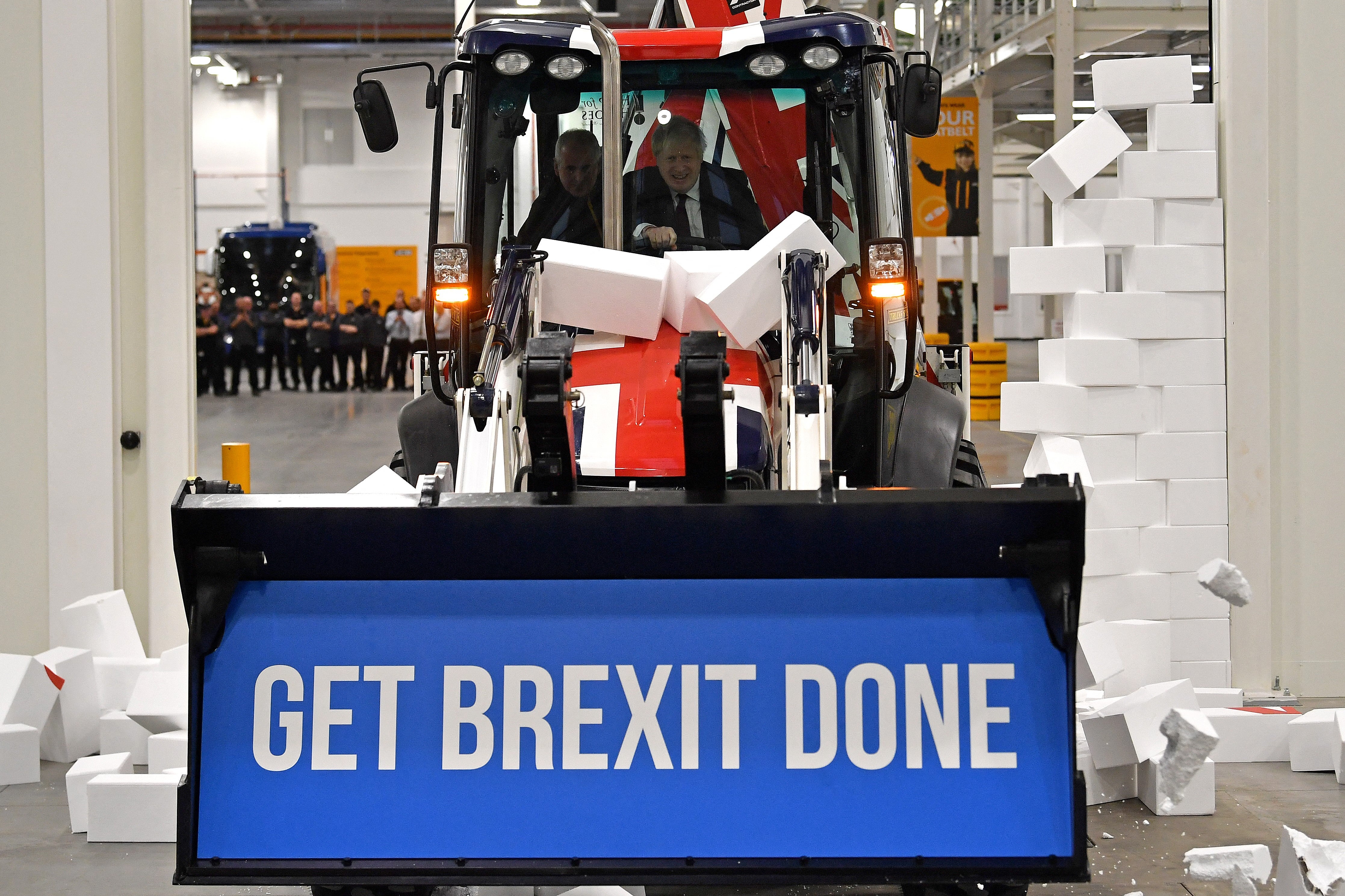 Boris Johnson drives a Union Jack-themed digger through a fake wall
