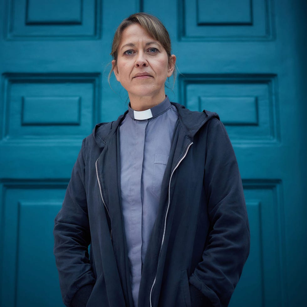 individual standing in front of a teal door wearing a clerical collar individual standing in front of a teal door wearing a clerical collar