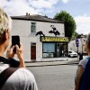 People gather to look at an artwork by street artist Banksy depicting two pelicans catching fish, painted on top of a fish-and-chips shop in Walthamstow, northeast London, on Aug. 9.