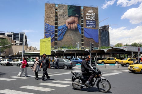 A motorist rides a scooter in Tehran near a billboard on the facade of a building depicting the strait of Hormuz with a caption in Persian reading “Forever in Iran’s Hand”.