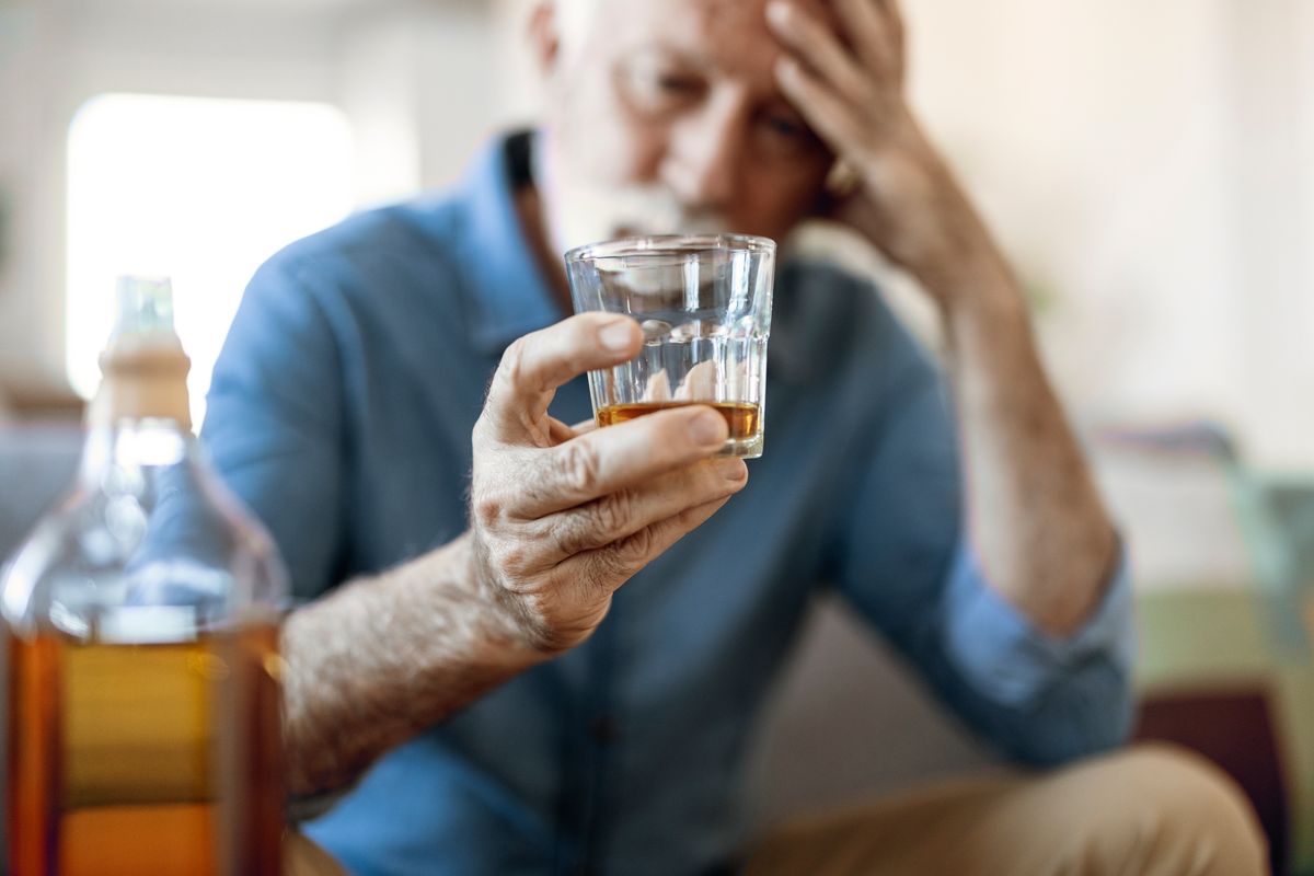 Drunk man drinking alcohol while holding a glass with alcohol