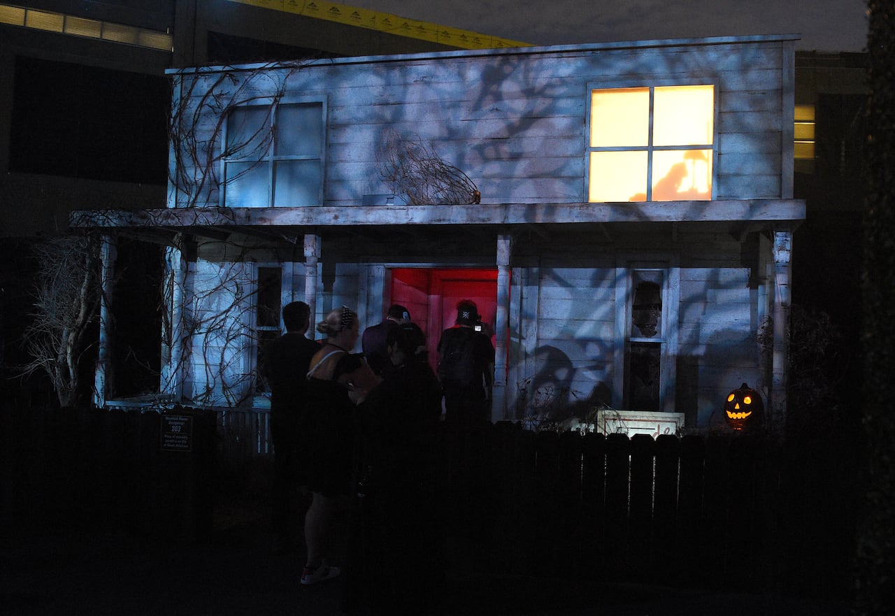 People line up to in front of a haunted house.