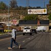 A man crosses a street in a town with a billboard that says "Welcome to Coalville" on the hillside at the end of the street. 