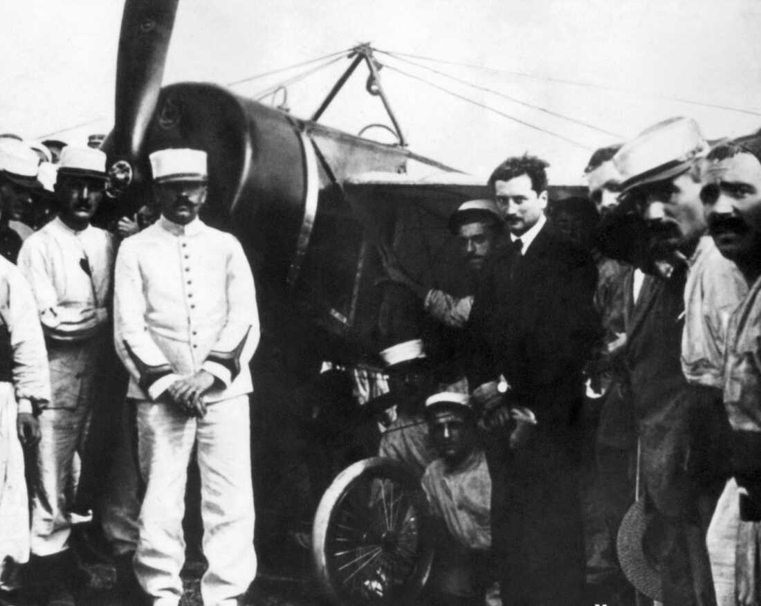 Roland Garros, in the dark suit, poses near the plane he flew across the Mediterranean in Tunisia in September 1913.