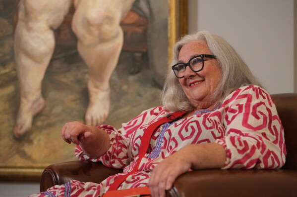 Sue Tilley, a model for British painter Lucian Freud, speaks in front of Freud's painting of her, titled "Sleeping by the Lion Carpet" during an interview in Sotheby's auction house in London, Thursday, May 28, 2026. (AP Photo/Kin Cheung)