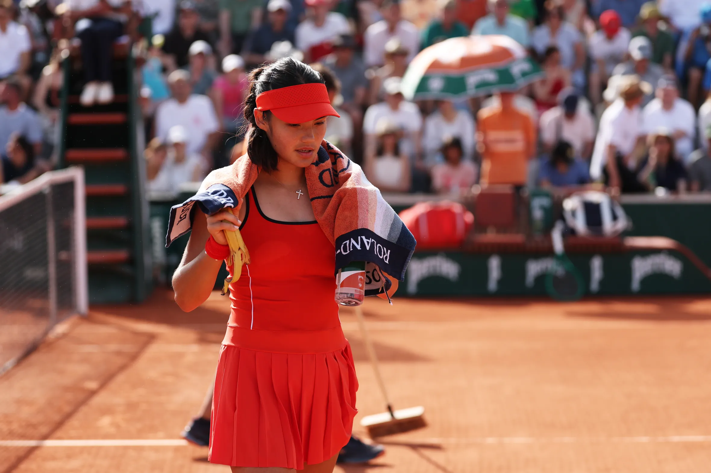 Emma Raducanu walking on a clay tennis court during the French Open.
