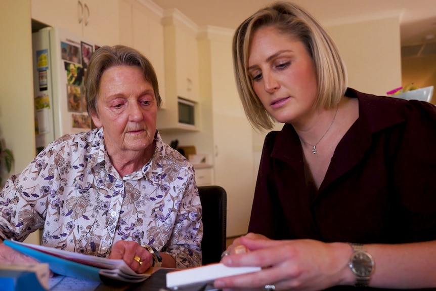 Two women sitting together looking and reading medication information