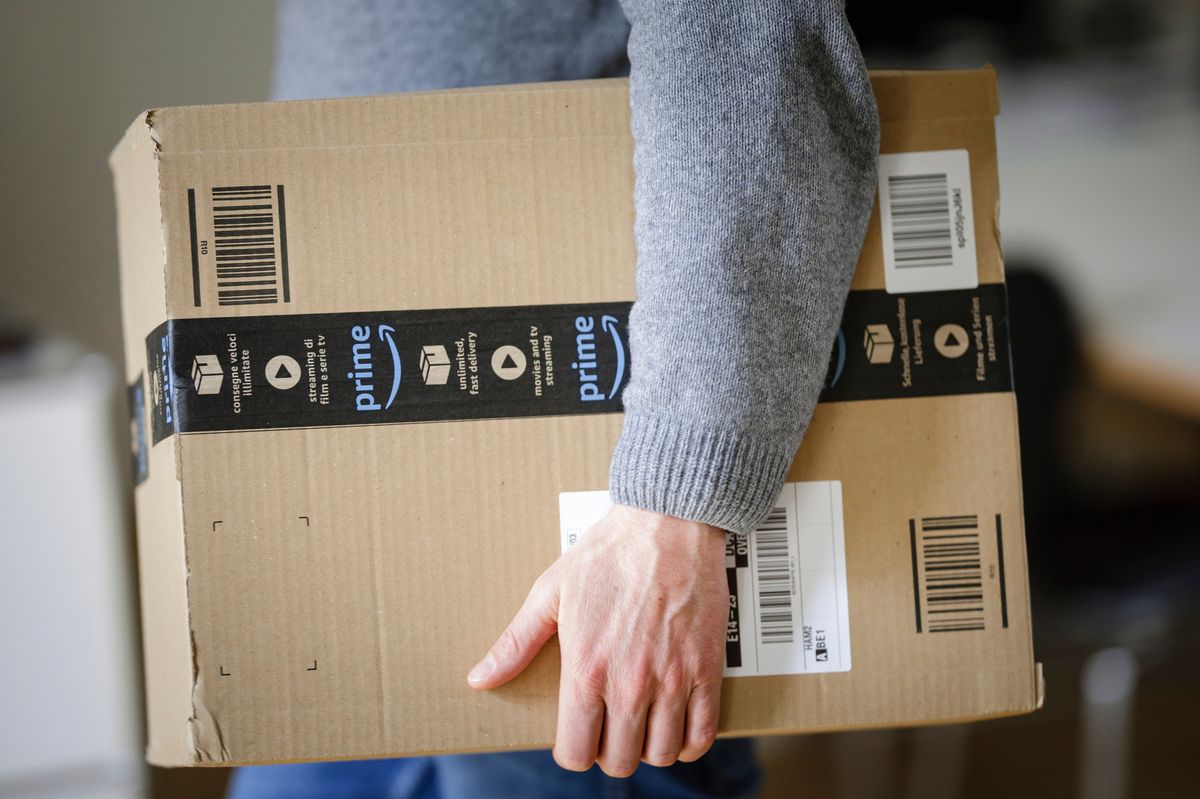 A man is holding an Amazon Prime package