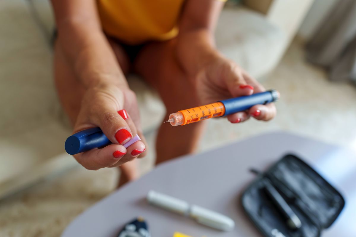 Unrecognizable middle-aged woman preparing an insulin pen to inject herself with a dose