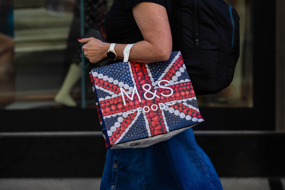 A customer carries an M&S-branded paper bag