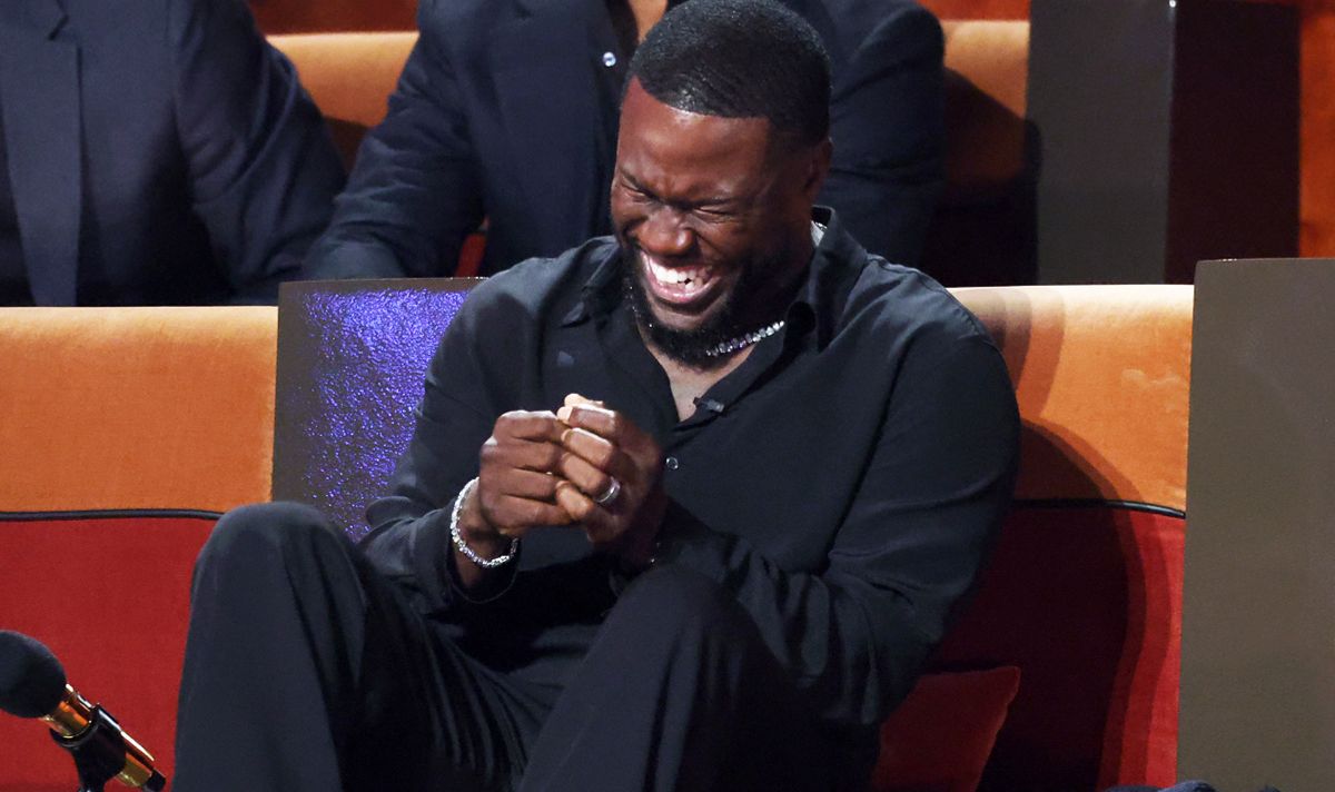 Man in black laughing on a sofa