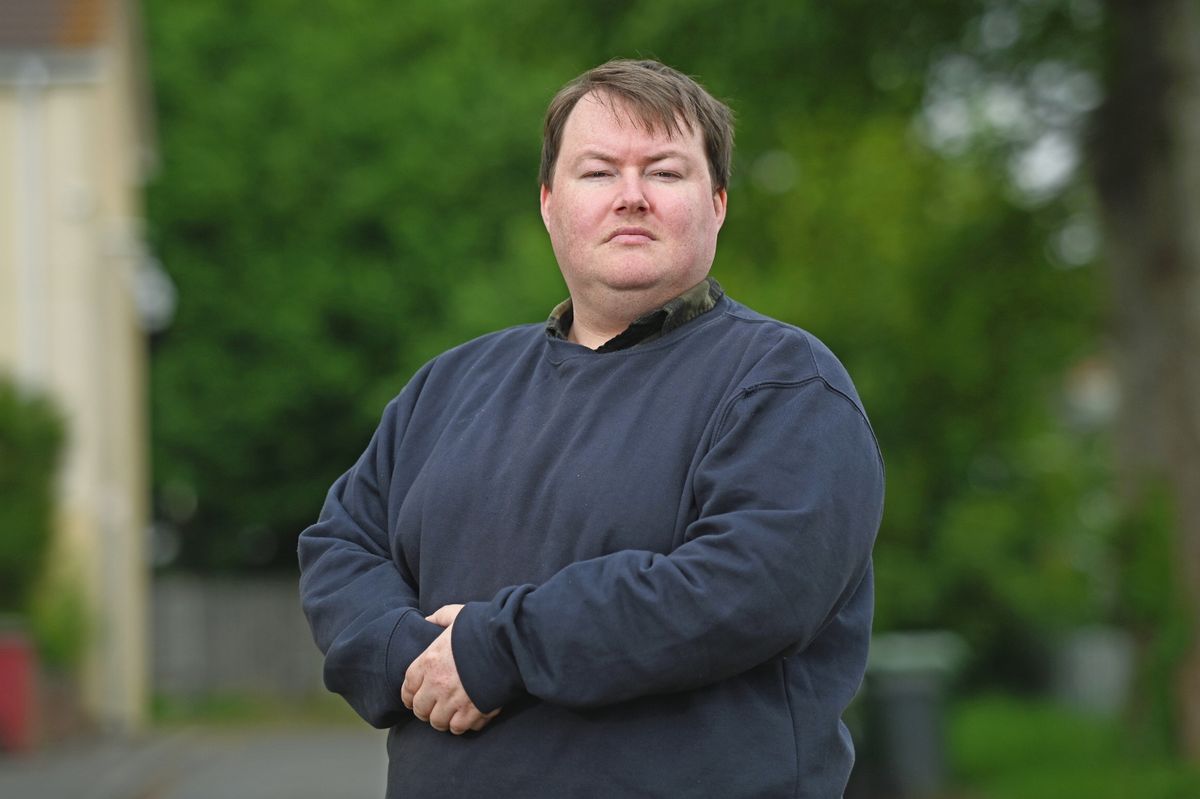 man stood with hands clasped in front of him