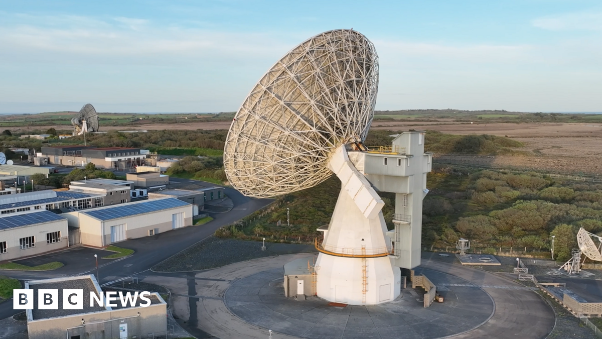 A drone shot of the satellite. It is surrounded by single level buildings and fields.