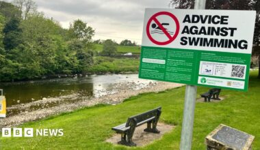 A sign saying Advice Against Swimming posted alongside a river in Lancashire.