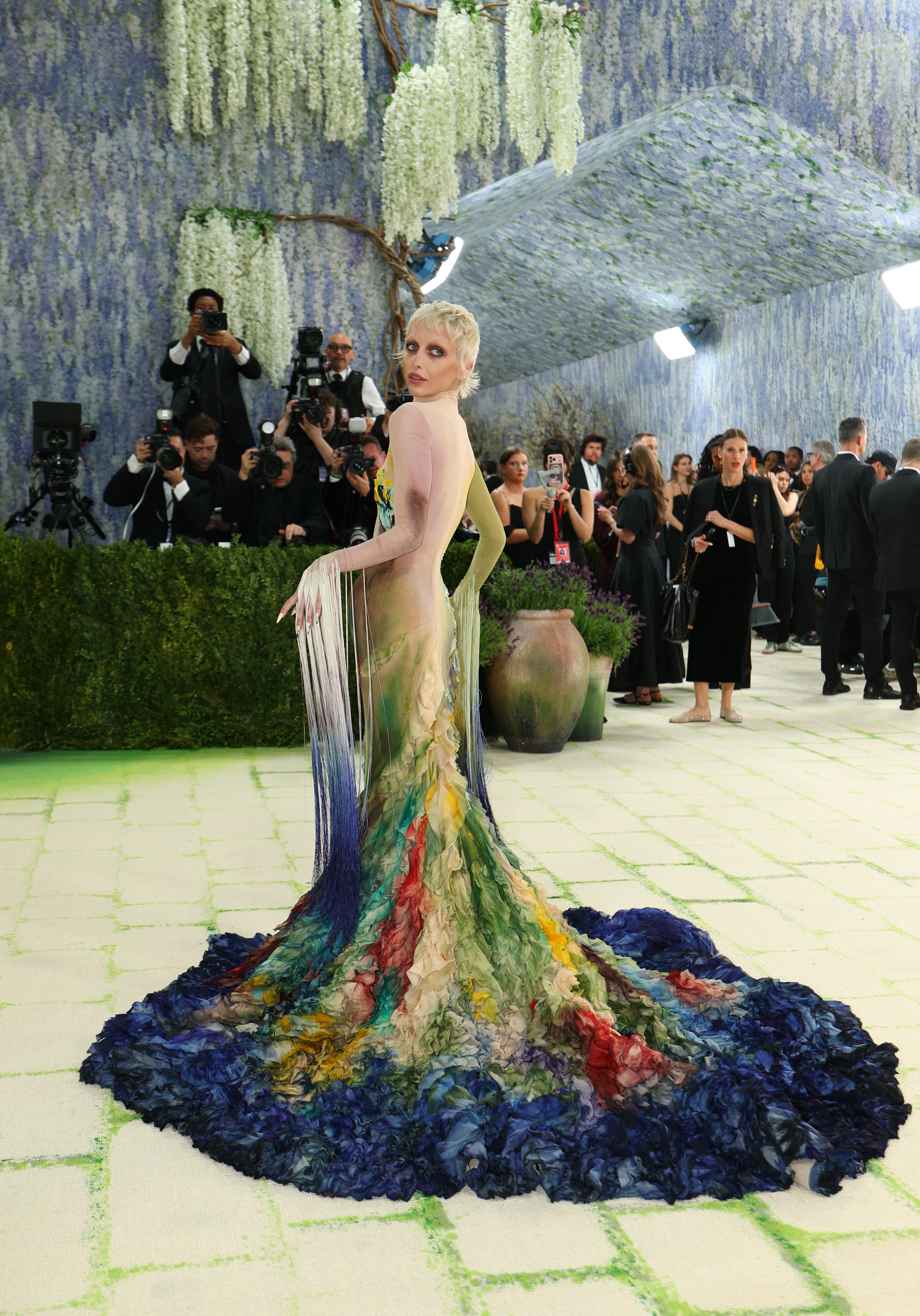 The gown features a mesh turtle neck and cascading fabric with a multi-toned watercolor design