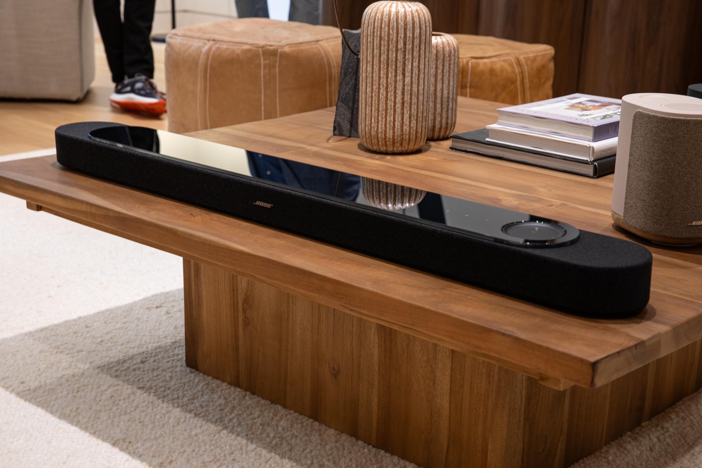 The Bose Lifestyle Ultra Soundbar in black on a wooden coffee table.