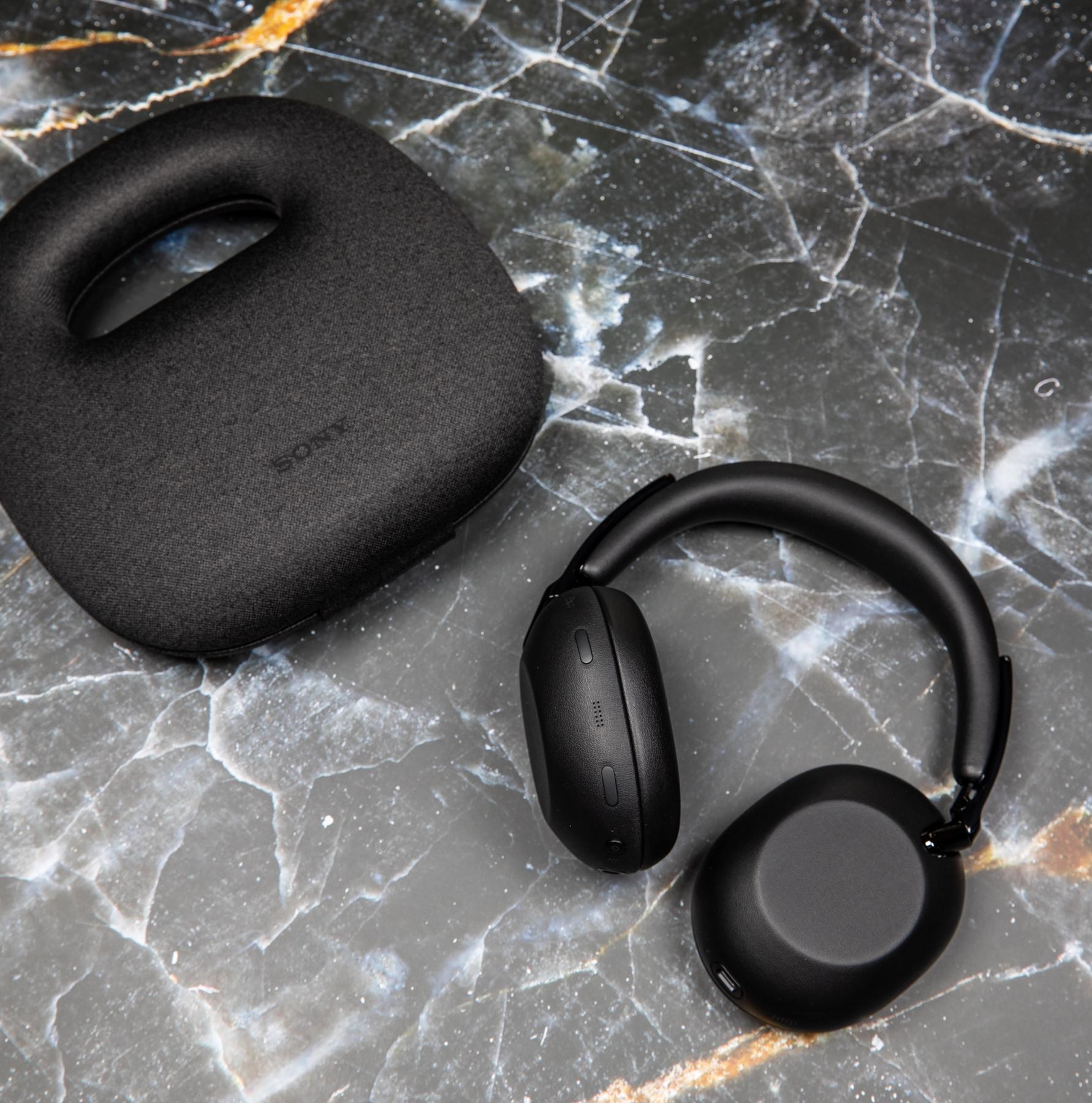 The Sony 1000X The Collexion headphones next to their carrying case on a marble surface.