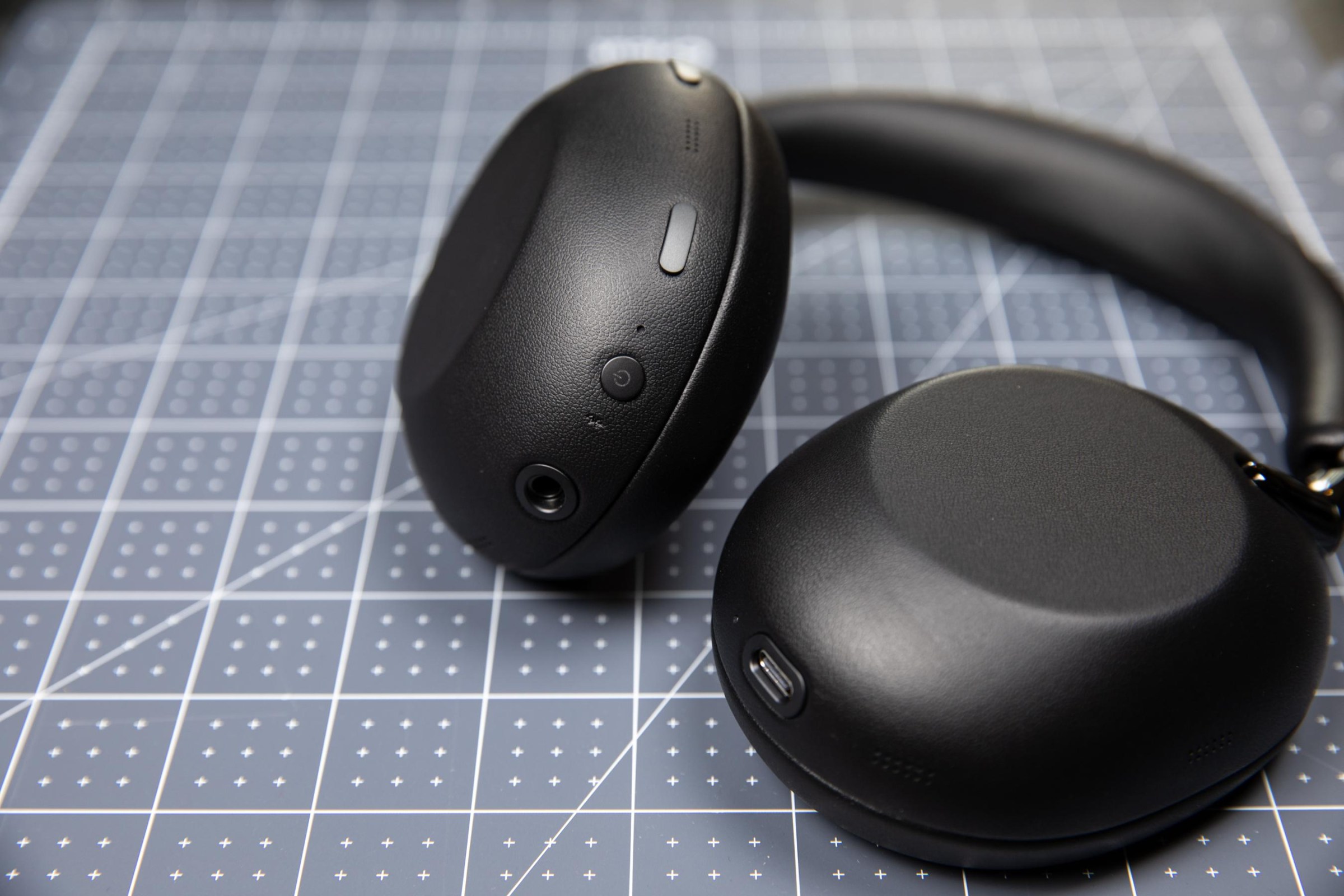 The Sony 1000X The Collexion headphones in black on a pale blue grid surface.