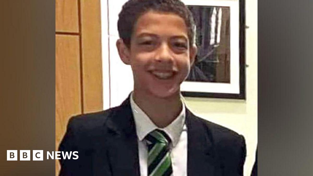 Noah Donohoe, with short black hair, wearing a white shirt, navy and green tie, and a black blazer.