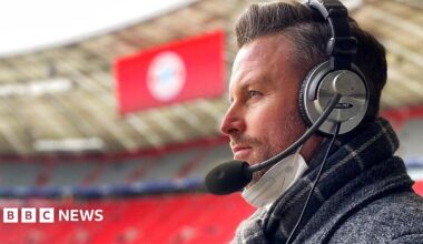 A side profile picture of a man wearing large over the ear headphones with a microphone attached to the side.