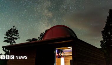 Part of Grizedale Observatory. The building has a dome on its roof with shimmering stars seen in the night sky above - the Milky Way.