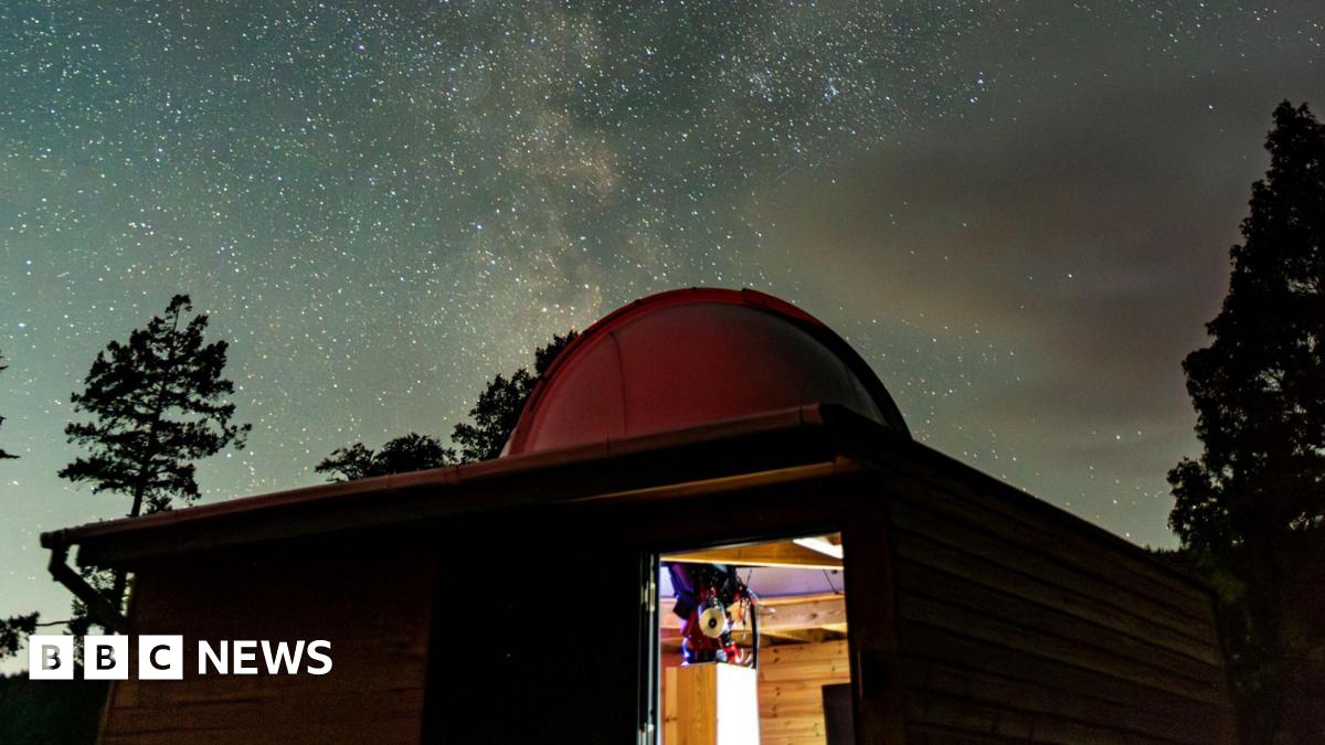 Part of Grizedale Observatory. The building has a dome on its roof with shimmering stars seen in the night sky above - the Milky Way.