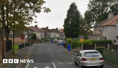 Google street view of semi-detached two storey houses lining a road with parked cars and trees.