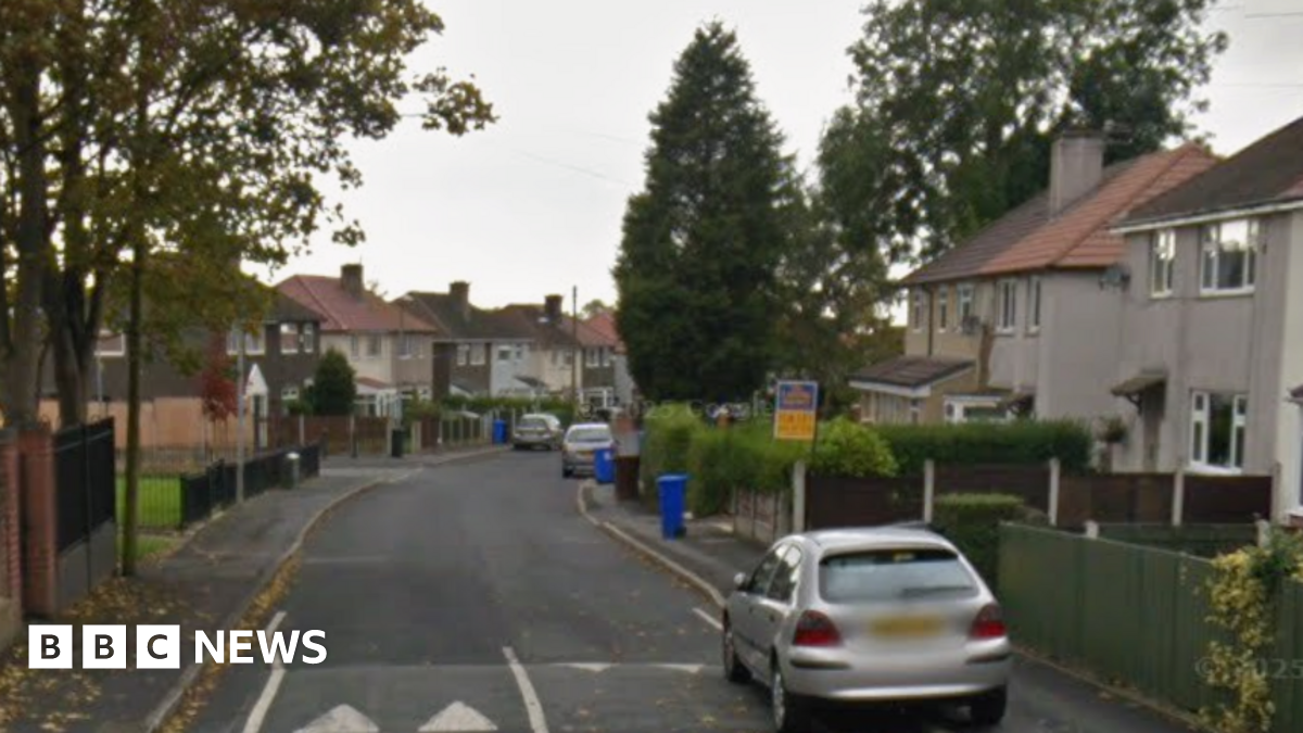 Google street view of semi-detached two storey houses lining a road with parked cars and trees.