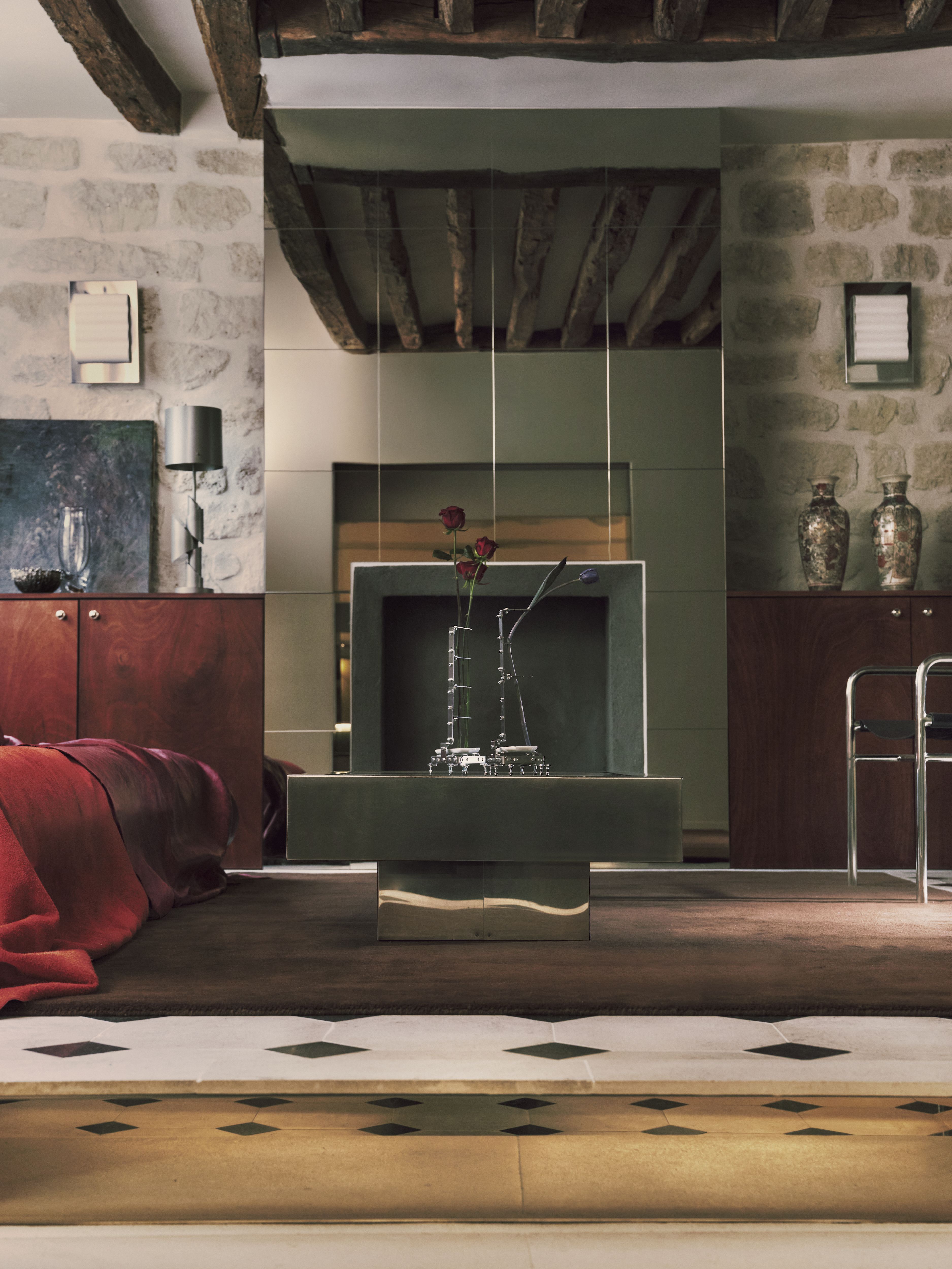 A sleekly designed apartment with tiled white and black checkered floors, chrome surfaces, brick walls, and occasional pops of red, ming green, and butter across linearly cut furniture.