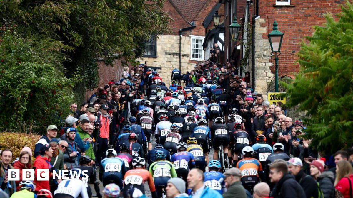 Riders in the Lincoln Grand Prix head up Michaelgate towards the cathedral and Castle Square. Large crowds are standing on both sides of the road.