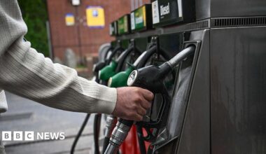 A person's hand on a petrol pump in a forecourt in a nondescript location in the UK