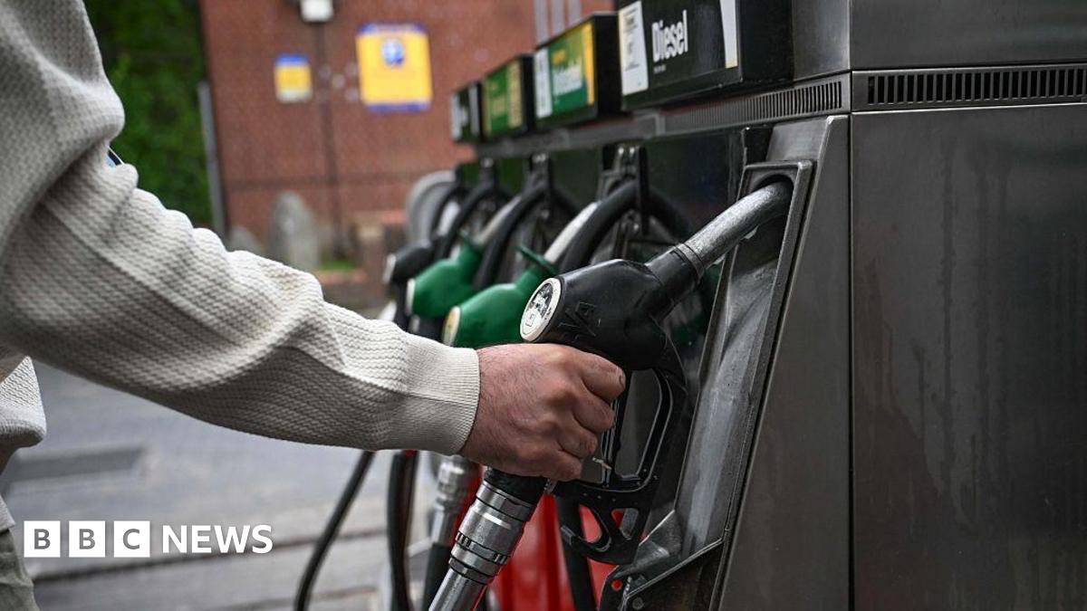 A person's hand on a petrol pump in a forecourt in a nondescript location in the UK