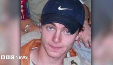 A headshot image of Luke Durbin. A young man wearing a navy Nike baseball cap. He is smiling and looking directly into the camera.
