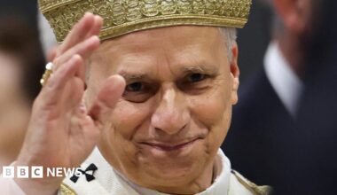 Close-up of Pope Leo's face with raised hand, as he leaves after a Mass on Sunday 2 May