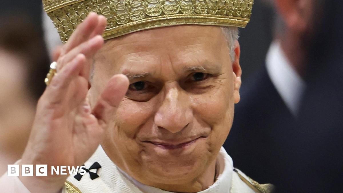 Close-up of Pope Leo's face with raised hand, as he leaves after a Mass on Sunday 2 May